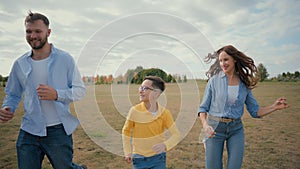 Happy joyful laughing Caucasian family father mother little boy child son kid playing running together park countryside