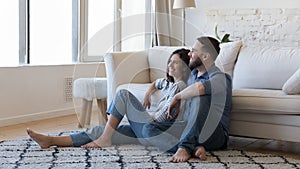 Happy joyful married couple resting on warm carpeted floor