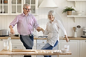 Happy joyful older husband and mature wife dancing to music