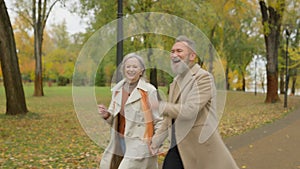 Happy joyful senior couple jumping dancing in autumn park love married partners outdoors funny healthy spouses two