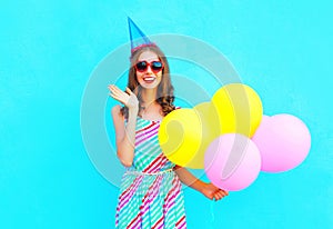 Happy joyful smiling young woman in a birthday cap with an air colorful balloons