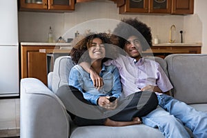 Happy joyful teen African couple watching TV, comedy movie