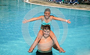 Happy joyful teenage boy and little pretty girl playing in swimming pool with natural ocean water