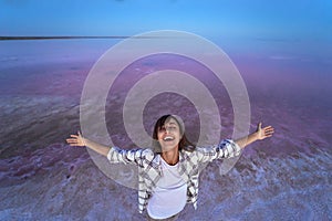 Happy joyful woman enjoying nature landscape at pink salt lake at evening