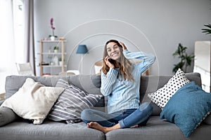 Happy joyful woman at home on the couch. Have a good time on the weekend, portrait of a positive girl talking on mobile