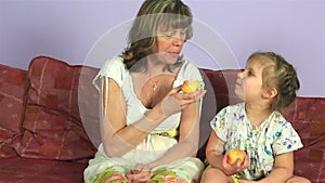 Happy joyful woman with little granddaughter eat delicious apples.