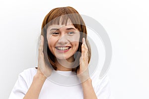 a happy, joyful woman smiles pleasantly with beautiful, even teeth and holds her hands near her face standing on a white