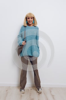 a happy, joyful woman stands on a light background in stylish clothes, smiling broadly at the camera