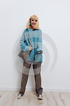 a happy, joyful woman stands on a light background in stylish clothes, smiling broadly at the camera