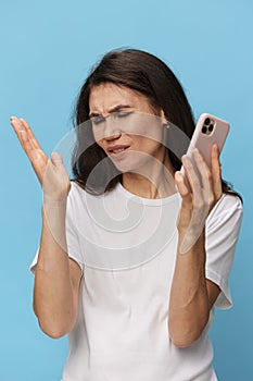 a happy, joyful woman stands with a phone in her hands spreading her arms to the sides. Horizontal photo on a light blue