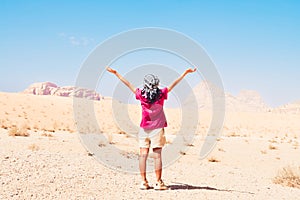 Happy joyful woman tourist stand with hands up on wadi rum desert on hike on holiday vacation in Wadi rum. Popular Wadi Rum desert