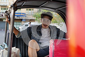 Happy and joyful Young Asian male traveler tourists riding a tuk tuk tour, rickshaw style transportation on the street