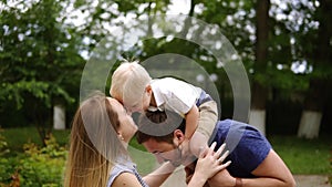 Happy joyful young family father, mother and little son having fun outdoors, playing together in summer park