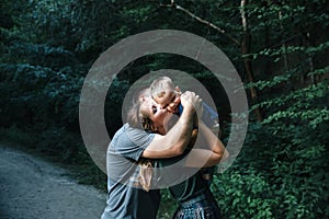 Happy joyful young family father, mother and little son having fun outdoors, playing together in summer park