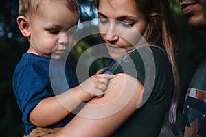 Happy joyful young family father, mother and little son outdoors, hugging together in summer park