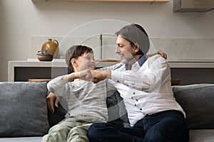 Happy joyful young father and teenage child son bumping fists.