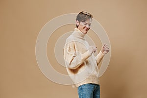 a happy, joyful young man with red hair, in a long sweater, dances merrily. Studio photography on a plain background