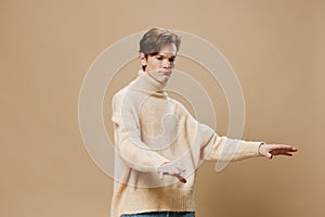 a happy, joyful young man with red hair, in a long sweater, dances merrily. Studio photography on a plain background
