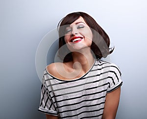 Happy joying young woman with closed eyes on blue