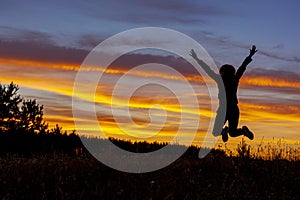 Happy jumping woman on the background of amazing sunset.