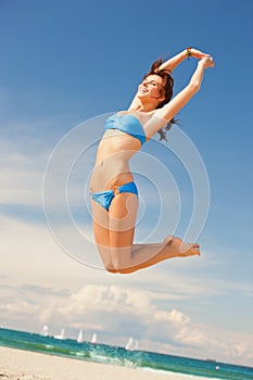 Happy jumping woman on the beach