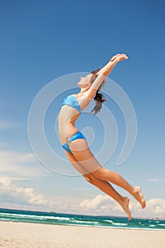 Happy jumping woman on the beach