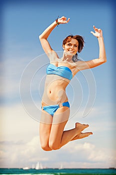 Happy jumping woman on the beach