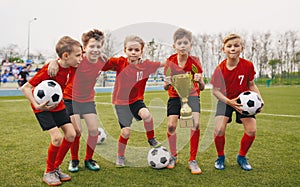 Happy Junior Sports Team. Young Boys in Soccer Team Holding Golden Cup and Soccer Balls