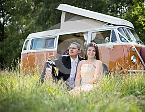 Happy Just Married Couple In a Classic Camper Van in a Field