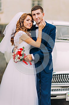 Happy just married couple posing in the background of vintage car