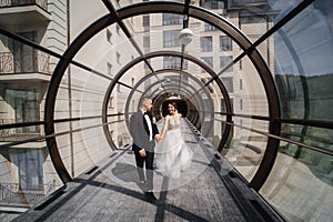 Happy just married couple walking beautiful round window in wedding day