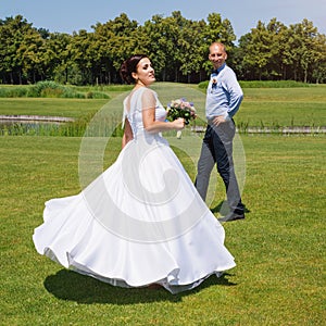 Happy just married young wedding couple having fun in the park. Bride and groom together, love and marriage theme.