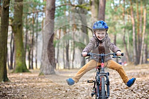 Happy kid boy of 3 or 5 years having fun in autumn forest with a bicycle on beautiful fall day. Active child wearing bike helmet.