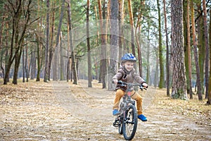 Happy kid boy of 3 or 5 years having fun in autumn forest with a bicycle on beautiful fall day. Active child wearing bike helmet.