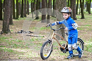 Happy kid boy of 4 years having fun in autumn forest with a bicycle on beautiful fall day. Active child making sports. Safety, lei