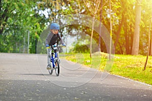 Happy kid boy of 5 years having fun in outdoor park with a bicycle on beautiful spring day. Active child making sports. Safety