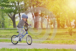 Happy kid boy of 5 years having fun in spring park with a bicycle on beautiful fall day. Active child wearing bike helmet