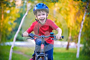 Happy kid boy of 6 years having fun in autumn forest with a bicycle on beautiful fall day. Active child making sports. Safety,