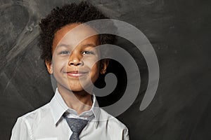 Happy kid boy on blackboard background. Smiling child face close up portrait