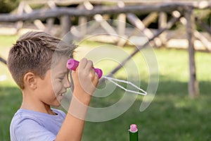 Happy kid boy blowing soap bubbles in a park