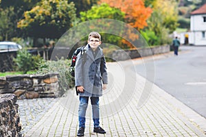 Happy kid boy with glasses and backpack or satchel. Schoolkid in stylish fashon coan on the way to middle or high school
