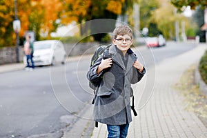 Happy kid boy with glasses and backpack or satchel. Schoolkid in stylish fashon coan on the way to middle or high school