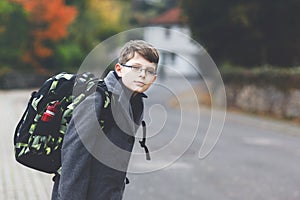 Happy kid boy with glasses and backpack or satchel. Schoolkid in stylish fashon coan on the way to middle or high school photo