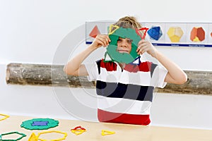 Happy kid boy having fun with building and creating geometric figures, learning mathematics and geometry