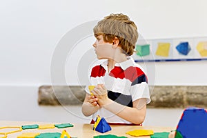 Happy kid boy having fun with building and creating geometric figures, learning mathematics and geometry
