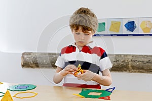 Happy kid boy having fun with building and creating geometric figures, learning mathematics and geometry