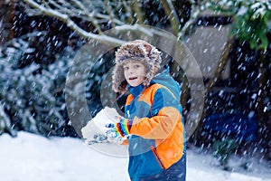 Happy kid boy having fun with snow in winter