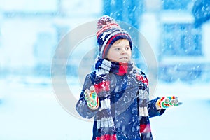 Happy kid boy having fun with snow in winter