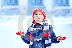 Happy kid boy having fun with snow in winter