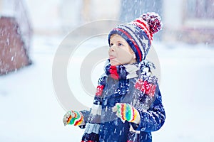 Happy kid boy having fun with snow in winter